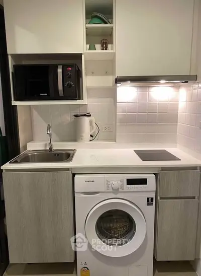 Modern compact kitchen with washing machine and microwave, ideal for urban living.