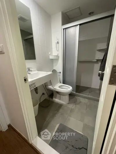 Compact modern bathroom with shower and sleek fixtures in a cozy apartment.