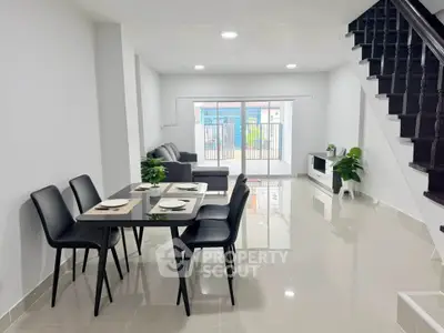 Modern open-plan living and dining area with sleek furniture and staircase, perfect for contemporary living.