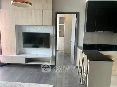 Modern living room with sleek TV setup and stylish kitchen bar area.