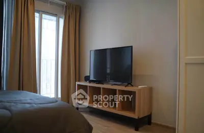 Modern bedroom with sleek TV setup and natural light from large window.