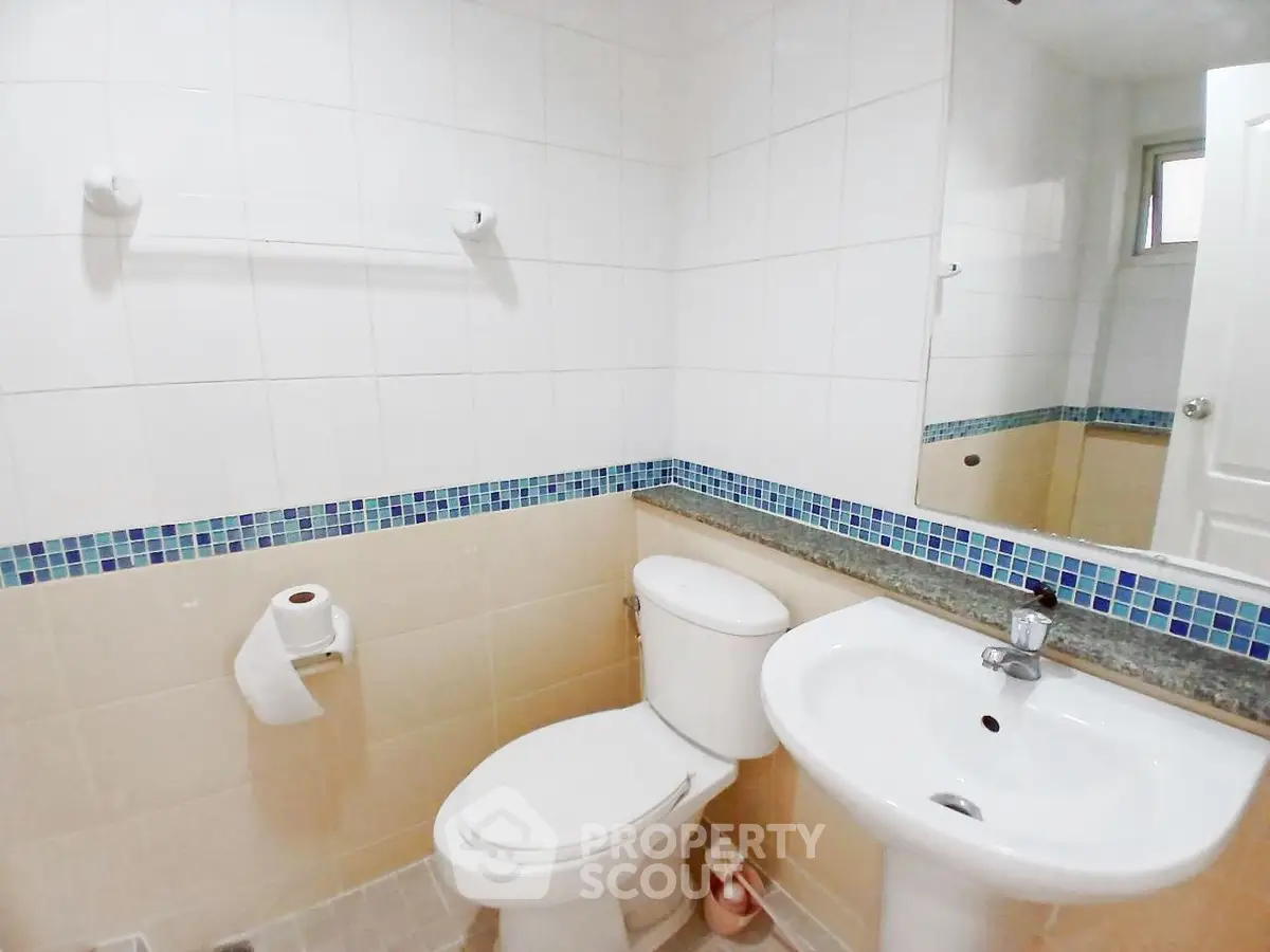 Modern bathroom with white fixtures and blue tile accents