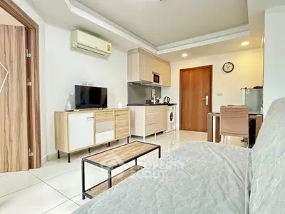 Modern living room with open kitchen, featuring sleek furniture and appliances.