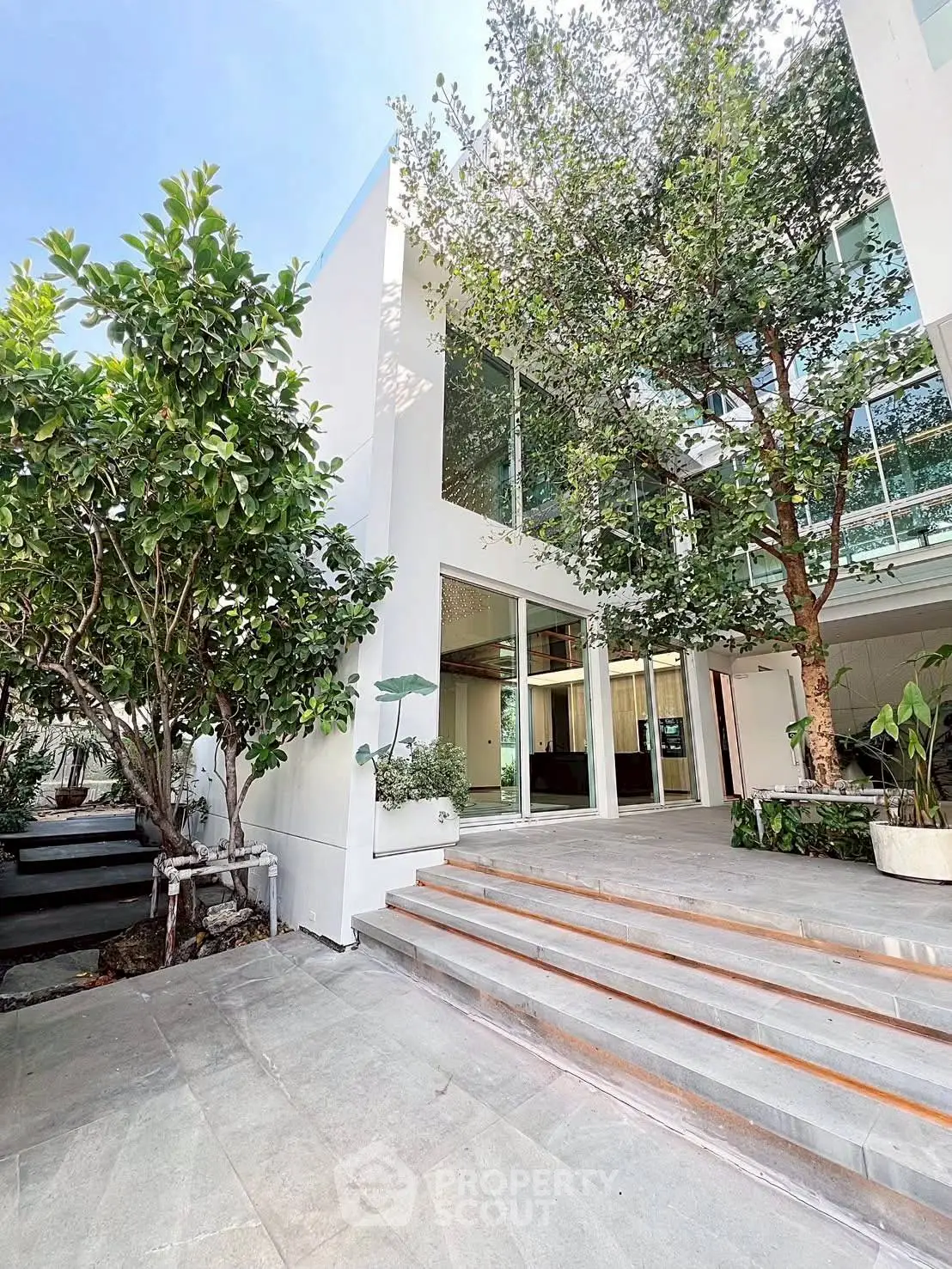 Modern architectural home exterior with lush greenery and large glass windows