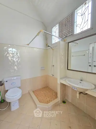 Spacious bathroom with tiled shower and modern fixtures in a bright, airy setting.