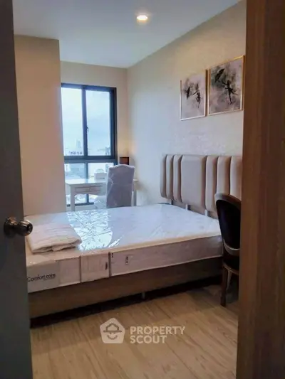 Cozy bedroom with modern decor and large window offering natural light.