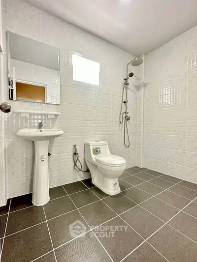 Modern bathroom with sleek fixtures and tiled walls, featuring a shower and toilet.