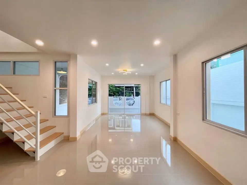 Spacious modern living room with large windows and elegant staircase