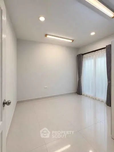 Spacious empty room with large windows and modern lighting, perfect for customization.