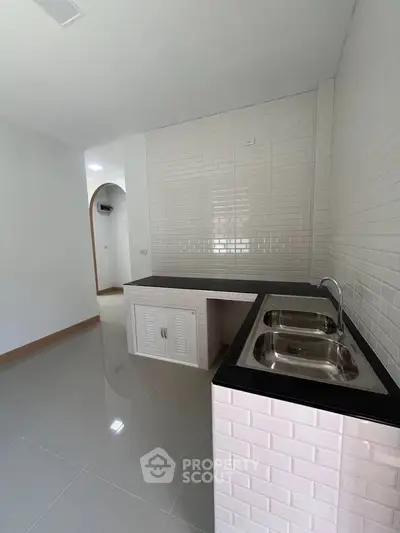 Modern kitchen with sleek black countertops and dual sink in minimalist design.