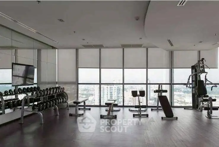 Spacious modern gym with city view, featuring state-of-the-art equipment and large windows.