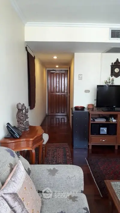 Charming living room with classic decor and wooden flooring, featuring a cozy seating area and entertainment setup.