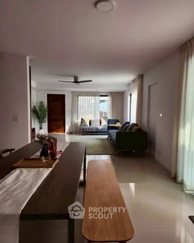 Spacious living room with modern decor and ample natural light, perfect for relaxation and entertaining.