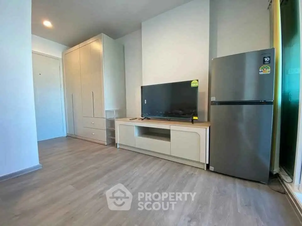 Modern living room with sleek furniture and stainless steel fridge, perfect for contemporary living.