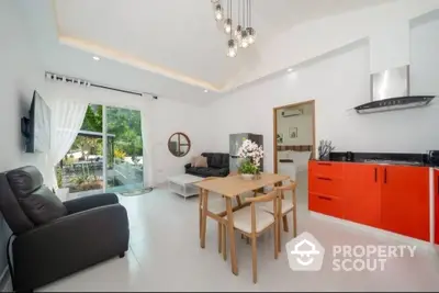 Modern open-plan living room with red kitchen cabinets and garden view