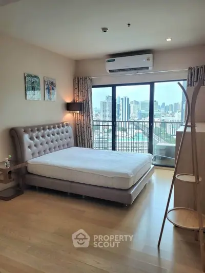 Spacious bedroom with city view and modern furnishings in high-rise apartment.