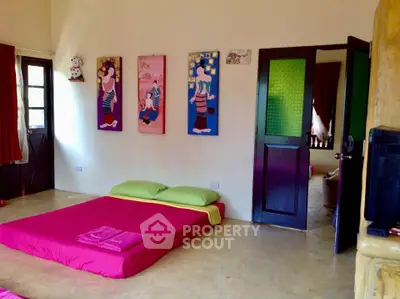 Charming bedroom with vibrant decor and artistic wall paintings, featuring a cozy floor bed and natural light.