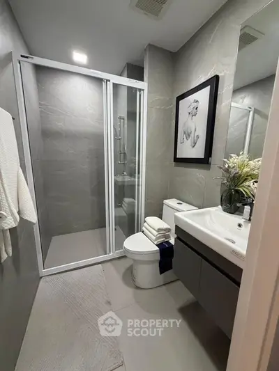Modern bathroom with sleek shower, elegant sink, and stylish decor in contemporary apartment.