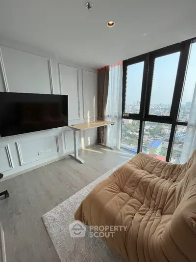 Modern living room with large window and city view, featuring a cozy sofa and flat-screen TV.