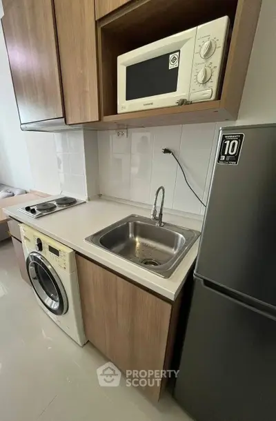 Modern kitchen with washing machine, microwave, and sleek cabinetry