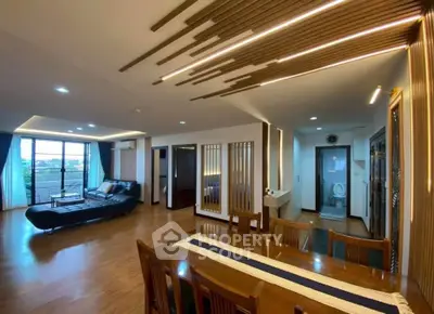 Spacious modern living room with stylish ceiling design and open layout, featuring a dining area and large windows.