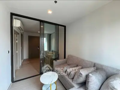 Modern living room with glass partition and cozy gray sofa in a stylish apartment.