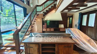 Luxurious living room with modern staircase and pool view, featuring elegant wooden furniture and large windows.