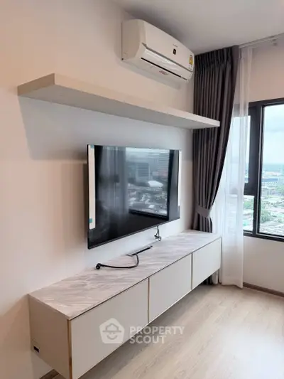 Modern living room with wall-mounted TV and air conditioning, featuring a sleek design and city view.