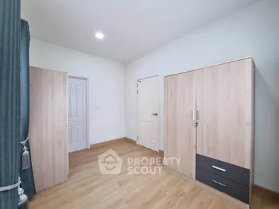 Spacious bedroom with wooden flooring and modern wardrobes, perfect for stylish living.