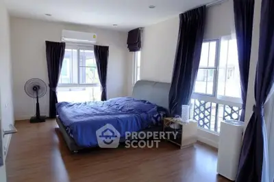 Spacious bedroom with modern decor and large windows for natural light.