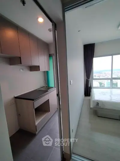 Modern compact kitchen with adjacent bedroom and city view