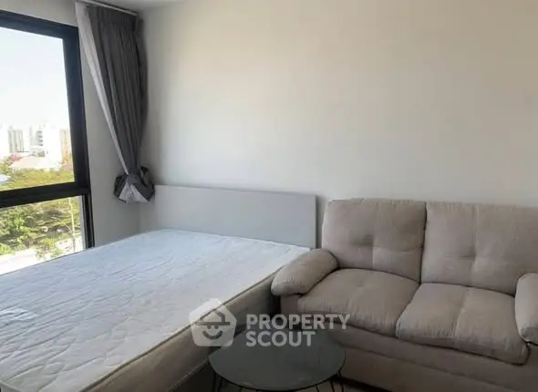 Cozy bedroom with a comfortable sofa and large window offering city views.