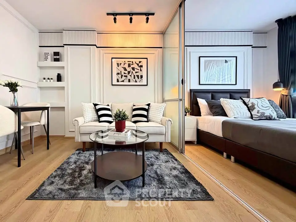 Modern studio apartment with stylish living area and cozy bedroom, featuring elegant decor and wooden flooring.