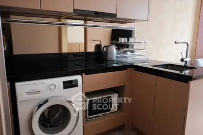 Modern kitchen with sleek black countertops, built-in appliances, and wooden cabinetry.