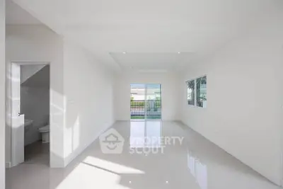 Spacious modern living room with large windows and glossy tile flooring, offering abundant natural light.