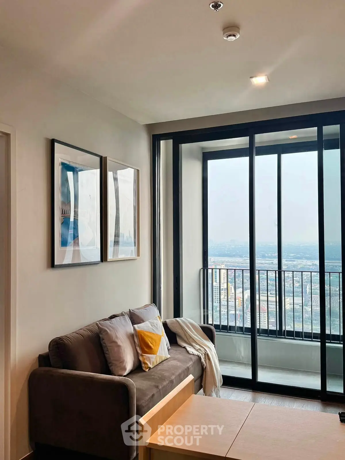 Modern living room with cozy sofa and stunning city view from large windows.