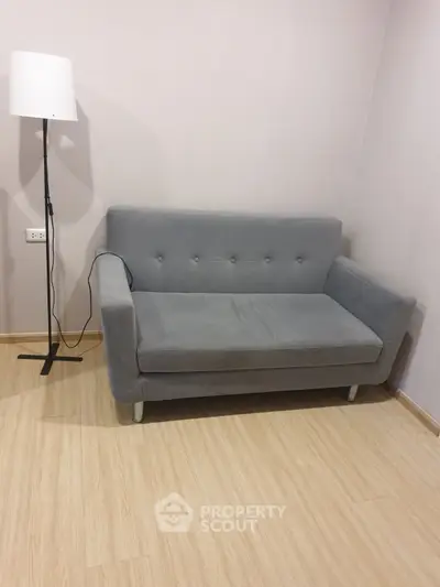 Cozy minimalist living room with modern gray sofa and sleek floor lamp.