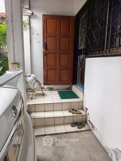 Cozy entrance with tiled steps and wooden door, perfect for welcoming guests.