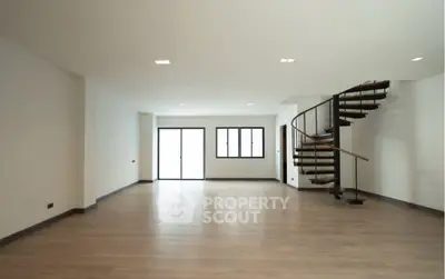 Spacious modern living room with elegant spiral staircase and large windows.