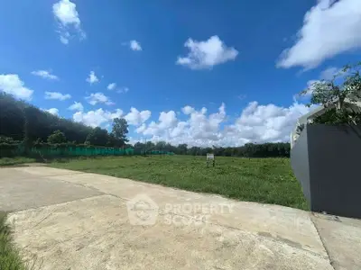 Expansive vacant land with lush greenery and clear blue skies, perfect for development opportunities.