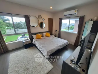 Spacious bedroom with modern decor and large windows offering natural light