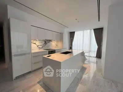 Luxurious modern kitchen with sleek white cabinetry and marble accents, featuring an island and floor-to-ceiling windows.