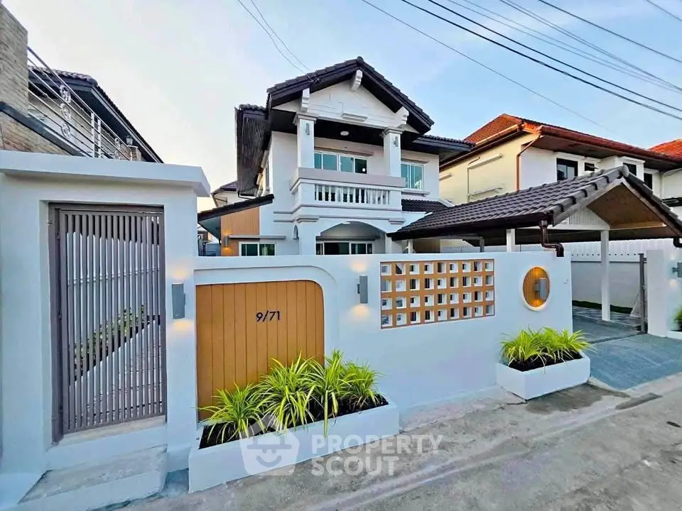 Charming two-story house with modern facade and gated entrance in a serene neighborhood.