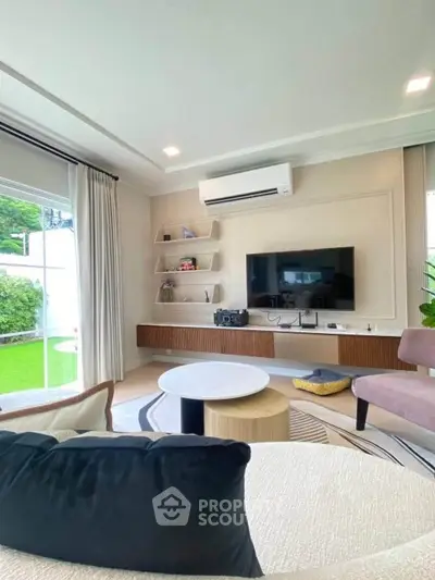 Modern living room with stylish decor, large window, and garden view, featuring a wall-mounted TV and air conditioning.