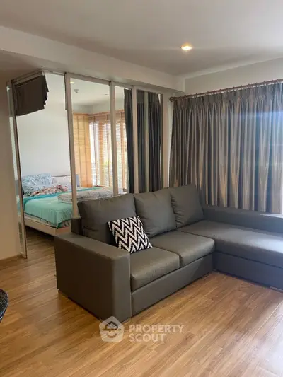 Modern living room with cozy sectional sofa and view into stylish bedroom