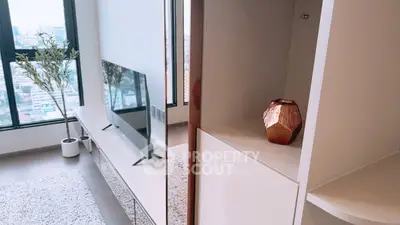 Modern living room with stylish decor and city view, featuring sleek TV stand and elegant vase.