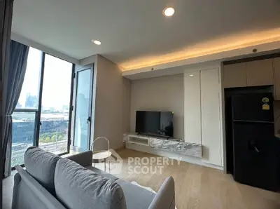 Modern living room with large windows and city view, featuring sleek furniture and a flat-screen TV.
