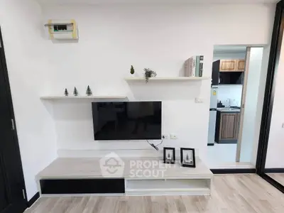 Modern living room with sleek TV setup and open view to stylish kitchen