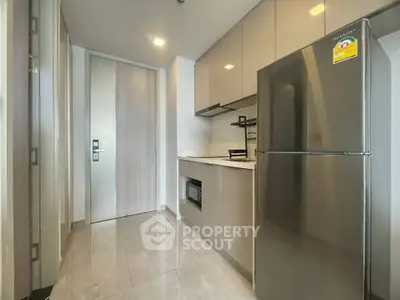 Modern kitchen with sleek cabinetry and stainless steel fridge in a compact layout.