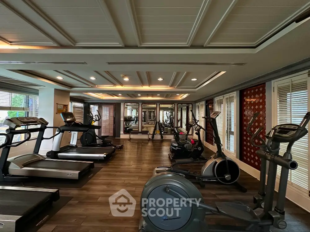 Luxurious gym with modern equipment and elegant ceiling design in upscale residential building.